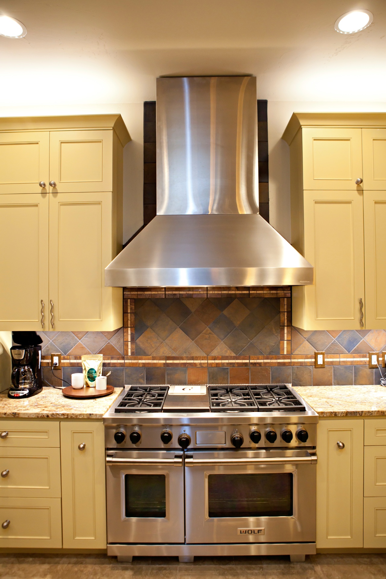 kitchen cabinets with beige paint and a huge stove with range hood
